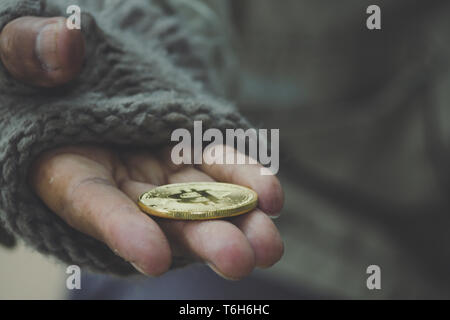 Homeless. Unhappy homeless man with black gloves is holding hand to get bit coins or help food donation from the people. Stock Photo