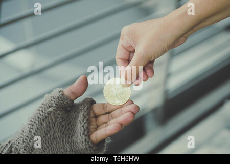 Homeless. Unhappy homeless man with black gloves is holding hand to get bit coins or help food donation from the people. Stock Photo