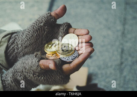 Homeless. Unhappy homeless man with black gloves is holding hand to get bit coins or help food donation from the people. Stock Photo