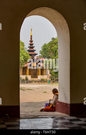 Buddhist monk sitting by the doorway of a Buddhist temple in the ancient city of Bagan in Myanmar. Stock Photo