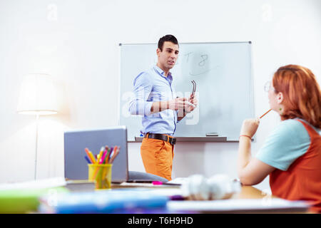 Nice pleasant young man taking off his glasses Stock Photo