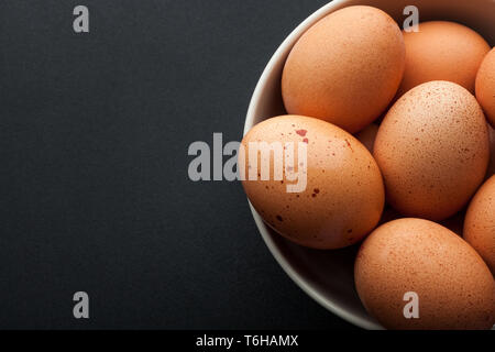 closeup brown eggs in bowl isolated on dark background Stock Photo