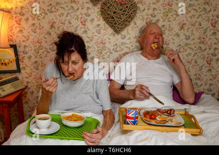 Elderly couple eating breakfast in bed Stock Photo