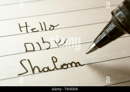 Beginner Hebrew language learner writing Hello Shalom word in Hebrew alphabet on a notebook close-up shot Stock Photo