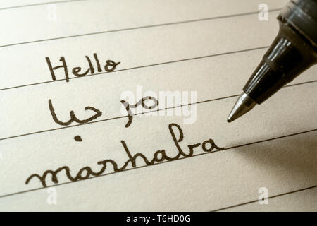 Beginner Arabic language learner writing Hello word Marhaba in abjad Arabic alphabet on a notebook close-up shot Stock Photo