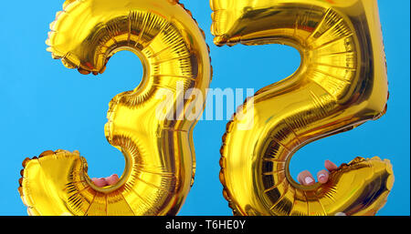 Gold foil number 35 celebration balloon on a blue Stock Photo