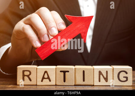Wooden blocks with the word Rating and the up arrow in the hands of the critic. Improving the quality of service of the hotel or restaurant. Good serv Stock Photo