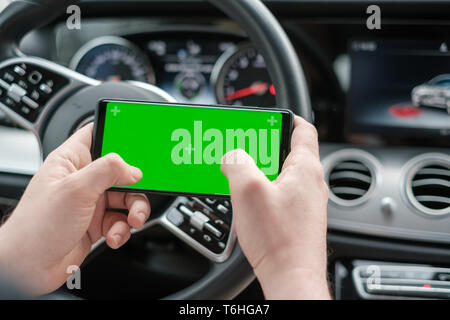 Man using smartphone on the background of a luxury class car dashboard Stock Photo