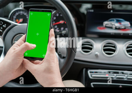 Man using smartphone on the background of a luxury class car dashboard Stock Photo