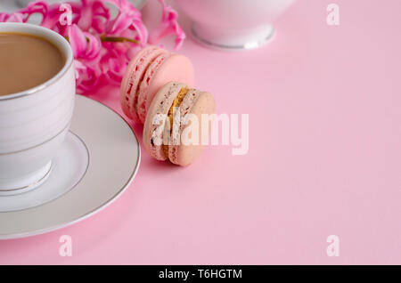 Cup of coffee with milk and macaroons or macarons on pastel pink background. Romantic morning concept. Copy space Stock Photo