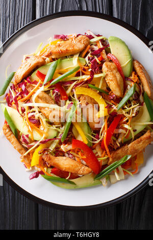 Delicious coleslaw salad with chicken, avocado and vegetables close-up on a plate on the table. Vertical top view from above Stock Photo