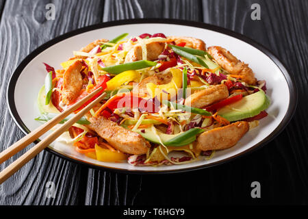 Colorful healthy asian cabbage salad with chicken, avocado and vegetables close-up on a plate on the table. horizontal Stock Photo