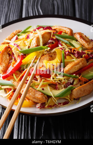 Delicious coleslaw salad with chicken, avocado and vegetables close-up on a plate on the table. vertical Stock Photo