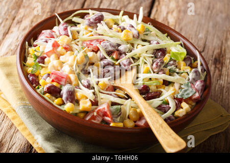 Vegetarian hearty cabbage salad with beans, corn, peppers and herbs close up in a dish on the table. horizontal Stock Photo