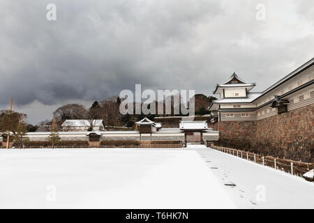 View along Gojukken Nagaya to the Hashizume-mon Tsuzuki Yagura, gate and turret at Kanazawa castle, daytime after snowfall. Dark grey clouds overhead. Stock Photo