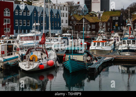 Little fishing and sailing boats in the harbour of Tórshavn in front of typical Faroese wooden and grass-covered houses (Faroe Islands, Europe) Stock Photo