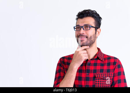 Portrait of happy bearded Persian hipster man thinking Stock Photo
