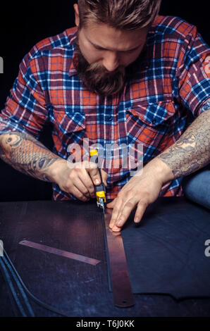 Professional Tanner creates a new leatherwork in his workshop Stock Photo