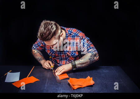 Artisan working with leather making quality products in his tanning shop Stock Photo