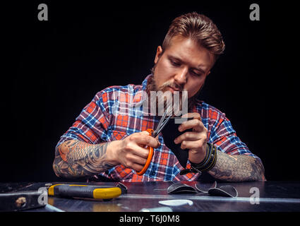 Worker of leather cuts out leather goods Stock Photo