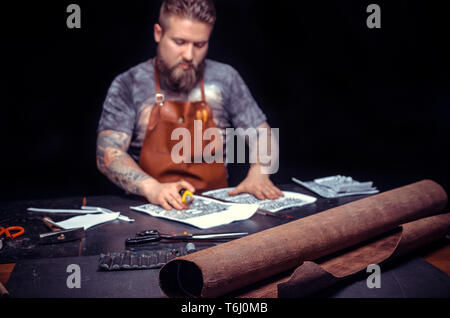 Artisan working with leather creating a new leather product in his workshop Stock Photo