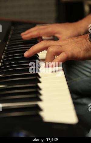 Two hands playing the electronic keyboard. Low Key Stock Photo