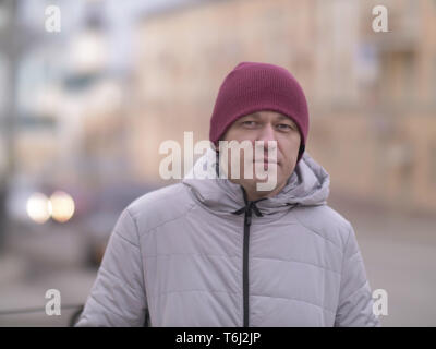 Portrait of a young man on a blurred background of the street, looking at the camera Stock Photo