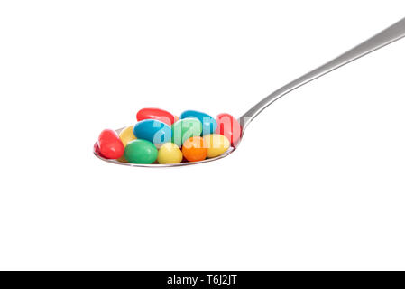 Multi-colored candies in a spoon on white background. Stock Photo