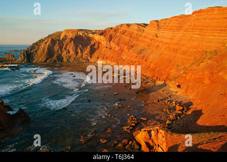 Glowing red sea cliff just before sunset. Near telheiro Beach, Vila do Bispo, West Algarve, Portugal. Stock Photo