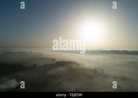 Dramatic winter high-level aerial landscape view of the sun breaking over north Oxfordshire, England and its powerful rays driving away frost and fog Stock Photo