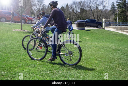 On the grass, in the park, off the trail, a family ventures with their bicycles. Stock Photo