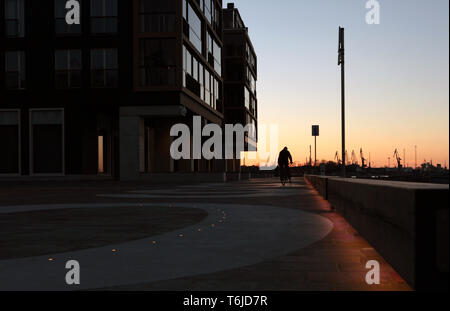 Cyclist cycling in front of a nightly skyline at modern Kalamaja district in Tallinn city, port area Stock Photo