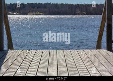 Idyllic view of the wooden pier in the lake or river mooring surface reflecting mirror sky Stock Photo