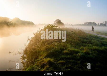 Early morning mist over the River Trent and the surrounding countryside with a man running, Nottinghamshire, England, UK Stock Photo