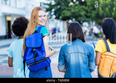 Young english female student with group of friends outdoor in the summer in the city