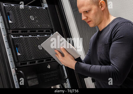 Male Technician Holding Digital Tablet Analyzing Servers in Datacenter Stock Photo