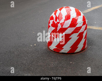 Bumped traffic bollard, made more visible in red and white tape Traffic and parking management. Stock Photo