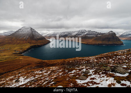 Panoramic view from Kap Enniberg to the small village Viðareiði, its fjords, Kunoy island and snow-covered mountains (Faroe Islands, Denmark, Europe) Stock Photo