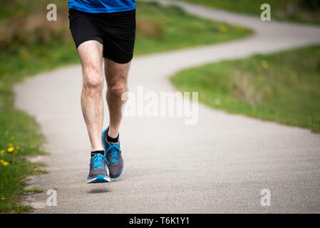 Senior man in 50s exercising and keeping fit by running in a park Stock Photo