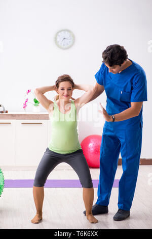 The pregnant woman doing physical exercies with instructor Stock Photo
