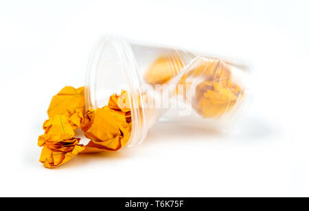Concept of garbage and pollution. Crumpled plastic cup with orange sheets of paper isolate on white background. Stock Photo