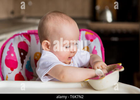 baby is 8 months and eats independently.the first lure baby.The baby with blue eyes does not want to eat vegetable puree.mom feeds from a small child' Stock Photo