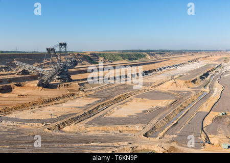 Brown coal open pit landscape with digging excavator in Germany Stock Photo