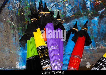 folded colorful paper umbrellas leaning at a painted wall in Chiang Mai Stock Photo