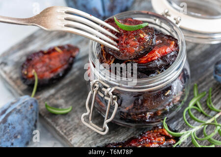 Spicy dried plum in a jar and a fork close-up. Stock Photo