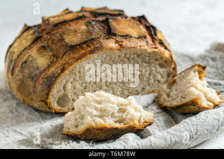 Piece of sourdough bread and a loaf of artisanal bread. Stock Photo