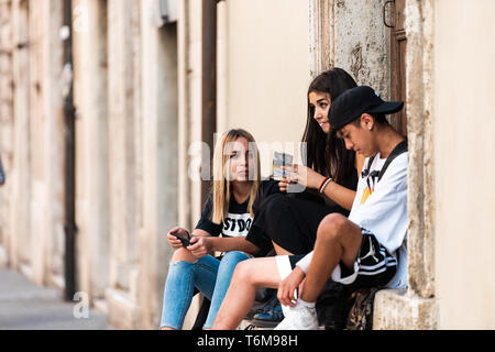 Perugia, Italy - August 29, 2018: City in Umbria with young people sitting by house on summer day smoking Stock Photo