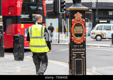 London, UK - September 12, 2018: Street road with people construction vest man walking in city downtown by Westminster sign post