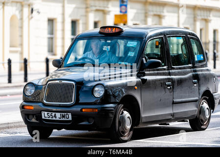 London, UK - September 14, 2018: Pimlico area closeup of expensive black taxi cab and driver on street road man behind wheel waiting in traffic