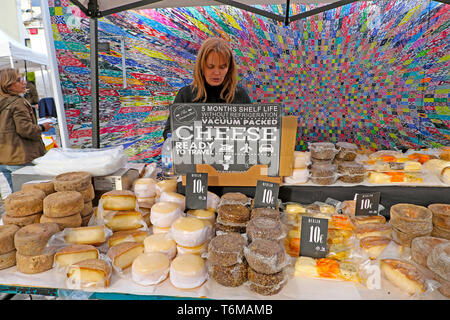 Woman selling various Portuguese local cheese round cheeses on food stall at LX Factory Market in Lisbon Lisboa Portugal  KATHY DEWITT Stock Photo